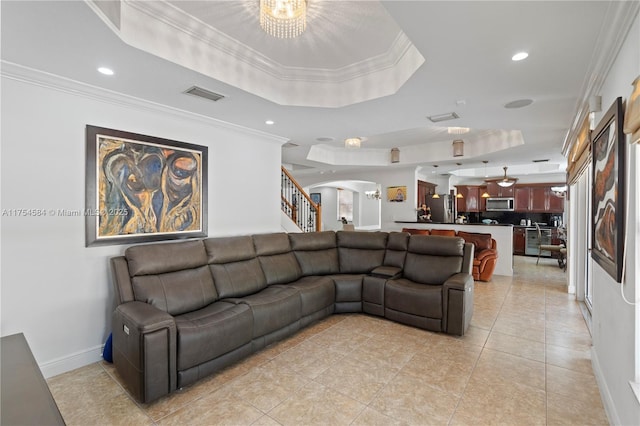 living area with visible vents, a raised ceiling, arched walkways, stairs, and crown molding