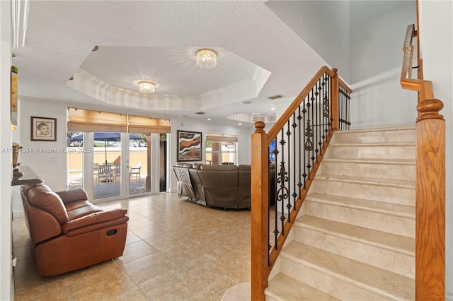 stairway featuring ornamental molding, a tray ceiling, french doors, and visible vents