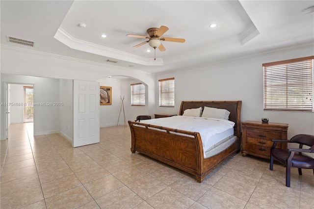 bedroom with a tray ceiling, arched walkways, visible vents, ornamental molding, and baseboards