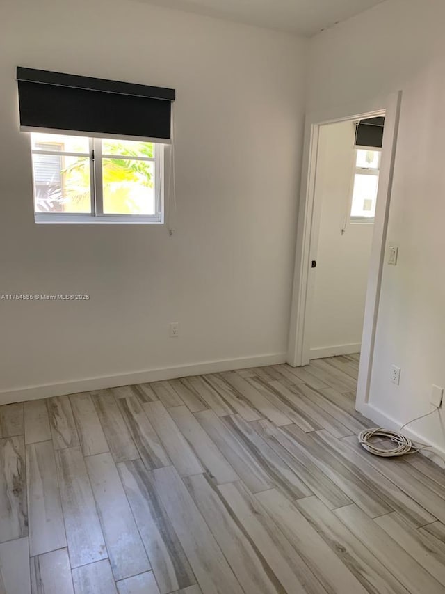 empty room featuring light wood-style floors and baseboards