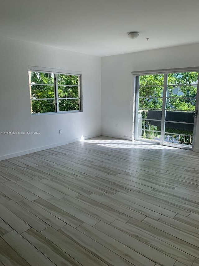 spare room with plenty of natural light, wood finished floors, and baseboards