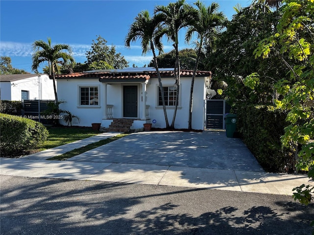 mediterranean / spanish-style house with driveway, a tile roof, a gate, and stucco siding