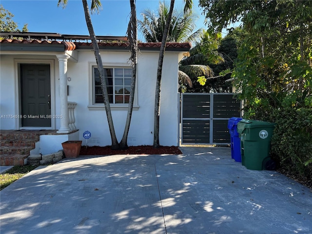 view of property exterior with a tile roof, a gate, and stucco siding