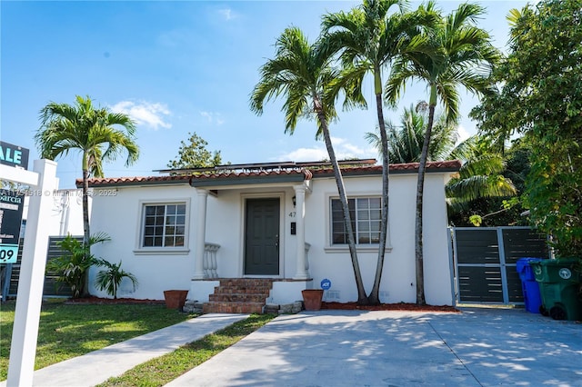 mediterranean / spanish house featuring stucco siding, a tile roof, a front lawn, and fence