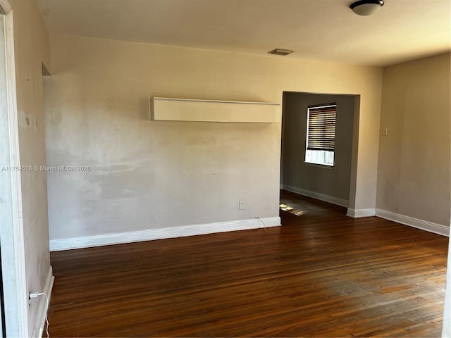 unfurnished room featuring wood finished floors, visible vents, and baseboards