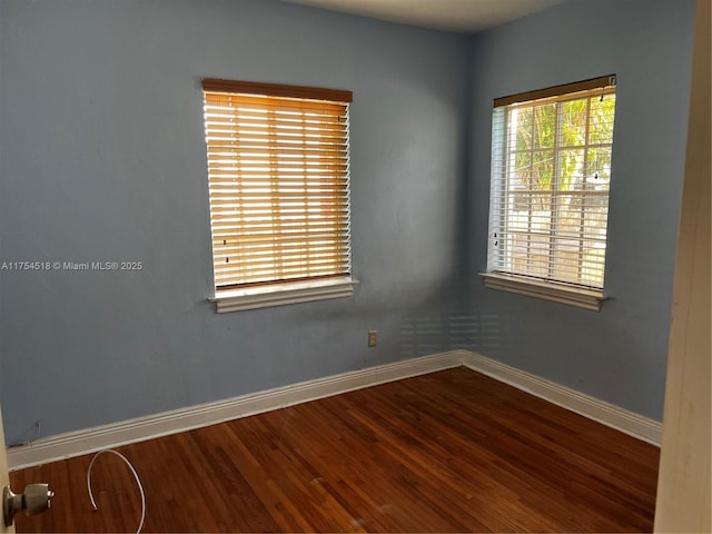 spare room featuring baseboards and wood finished floors