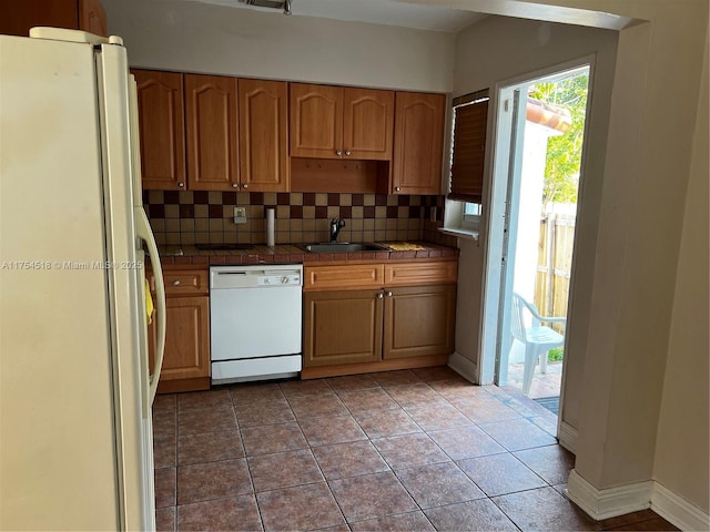 kitchen featuring white appliances, a sink, tile counters, and tasteful backsplash