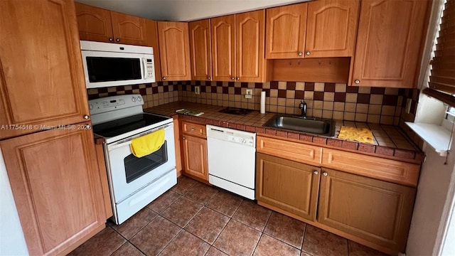 kitchen with tile counters, decorative backsplash, a sink, dark tile patterned flooring, and white appliances