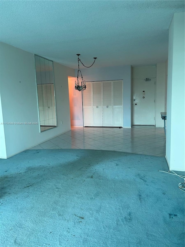 empty room with carpet floors, a textured ceiling, and tile patterned floors