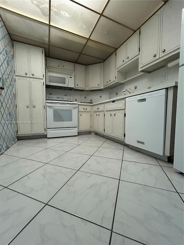 kitchen with a paneled ceiling, white appliances, marble finish floor, and light countertops