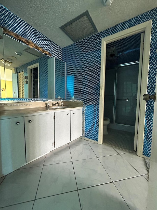 full bath with a textured ceiling, toilet, vanity, tile walls, and marble finish floor