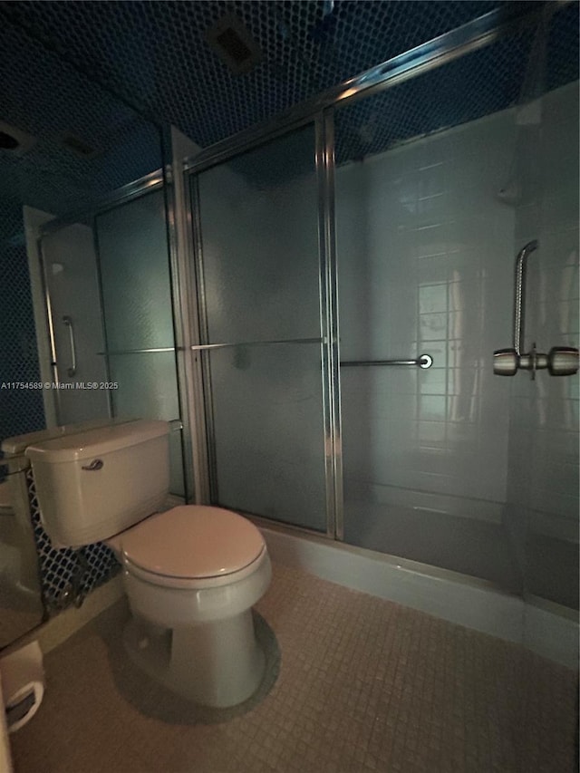 full bath with a shower stall, toilet, and tile patterned floors