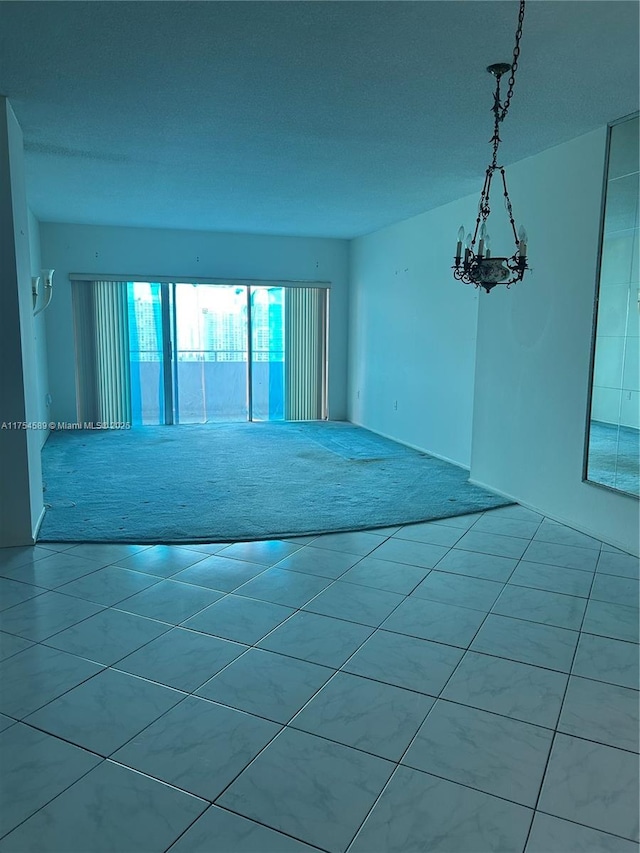 unfurnished room with carpet, tile patterned flooring, and an inviting chandelier