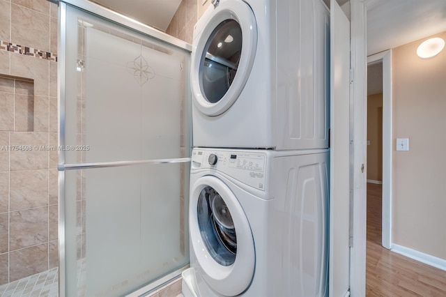 laundry room with laundry area, baseboards, stacked washing maching and dryer, and wood finished floors