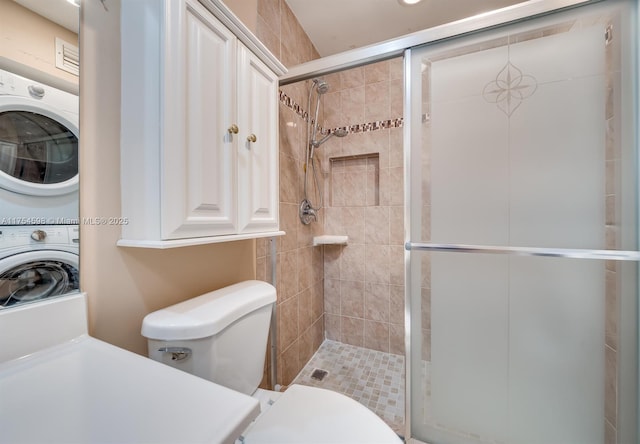 bathroom with toilet, stacked washer and dryer, and a shower stall