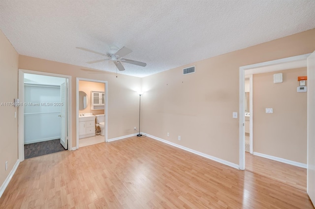 unfurnished bedroom with a closet, visible vents, a textured ceiling, light wood-type flooring, and baseboards