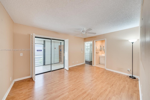 spare room featuring light wood-style flooring, baseboards, ceiling fan, and a textured ceiling