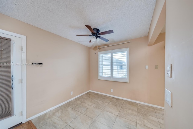 empty room with a ceiling fan, a textured ceiling, baseboards, and light tile patterned floors