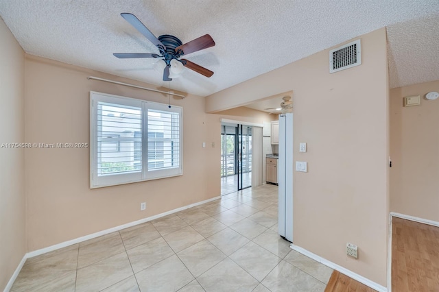 empty room with a ceiling fan, visible vents, a textured ceiling, and light tile patterned flooring