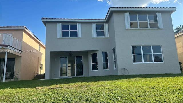 back of property with a lawn and stucco siding