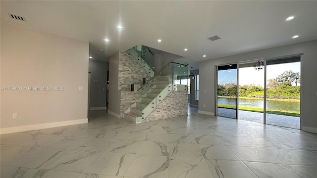 unfurnished room with marble finish floor, a water view, and visible vents