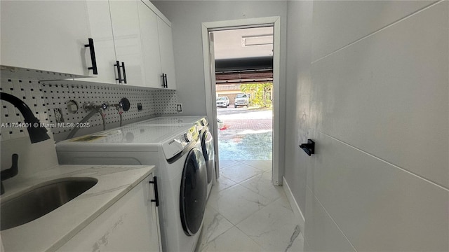 washroom featuring cabinet space, marble finish floor, and separate washer and dryer