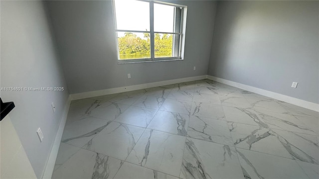 spare room featuring marble finish floor and baseboards