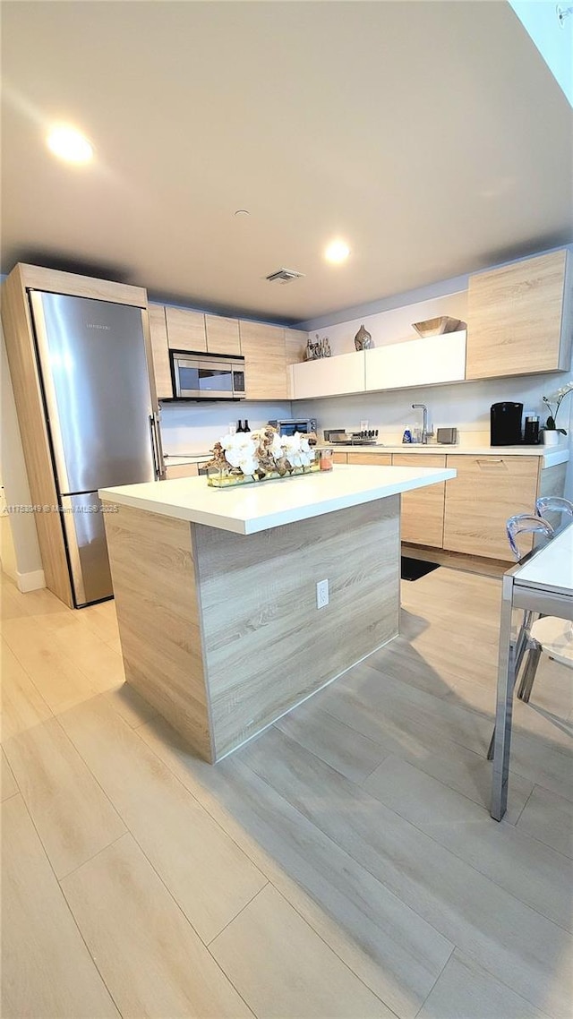 kitchen with light countertops, visible vents, light brown cabinetry, appliances with stainless steel finishes, and modern cabinets