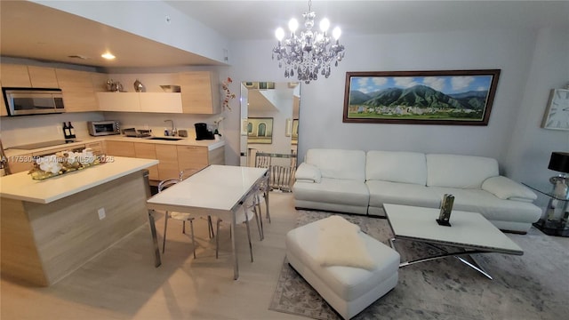 kitchen with light countertops, stainless steel microwave, open floor plan, light brown cabinets, and a sink