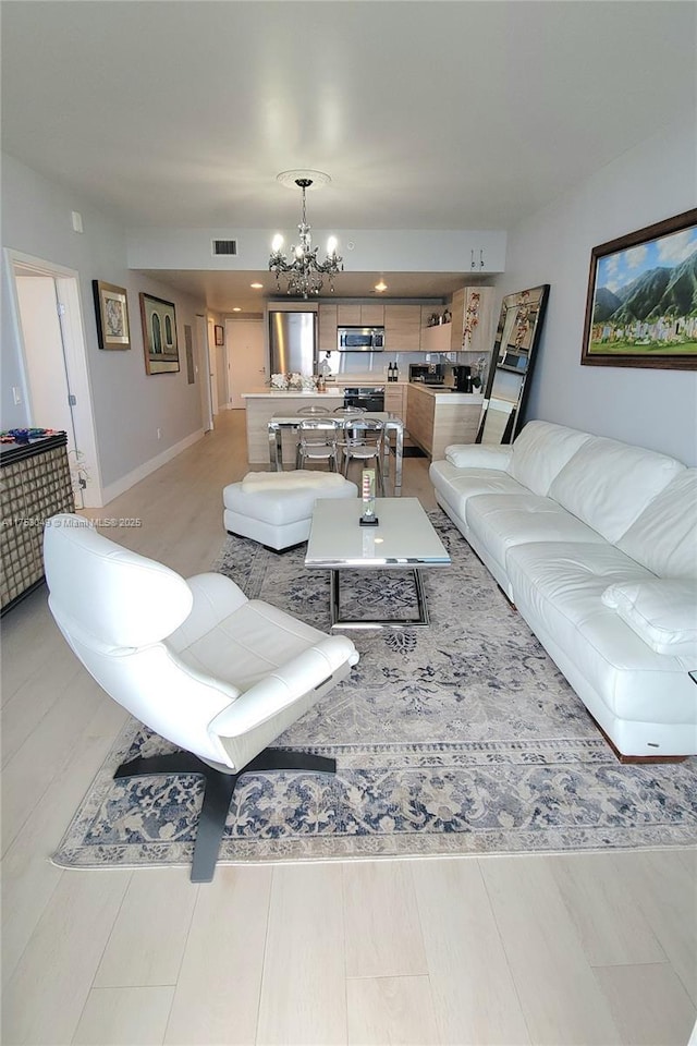 living area featuring a chandelier, visible vents, and baseboards