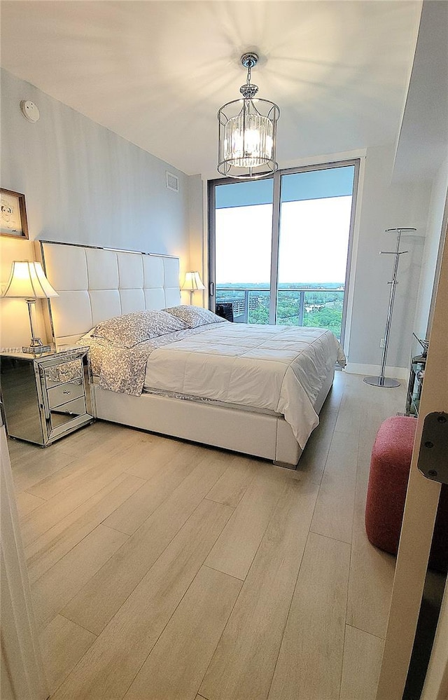 bedroom with visible vents, a notable chandelier, and wood finished floors