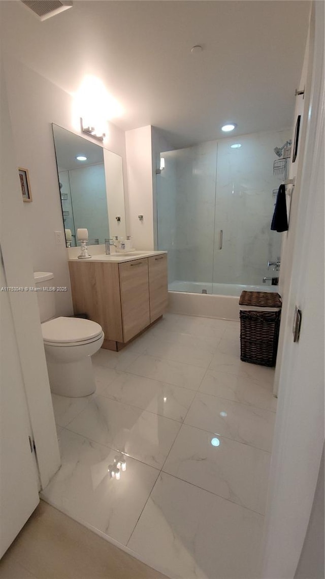 bathroom featuring marble finish floor, combined bath / shower with glass door, vanity, and toilet