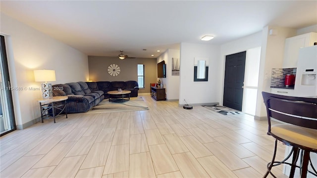 living room with light wood-style floors, ceiling fan, and baseboards