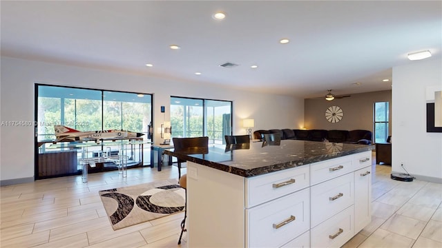 kitchen featuring recessed lighting, open floor plan, white cabinets, and dark stone countertops