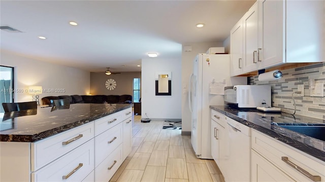 kitchen with white appliances, decorative backsplash, open floor plan, dark stone countertops, and white cabinetry