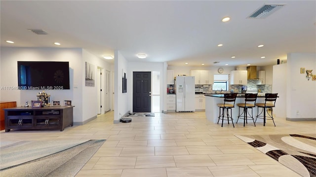 living room with baseboards, visible vents, and recessed lighting