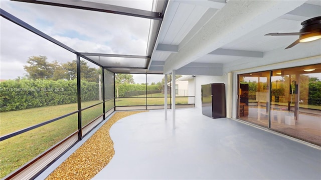 unfurnished sunroom featuring ceiling fan and beamed ceiling