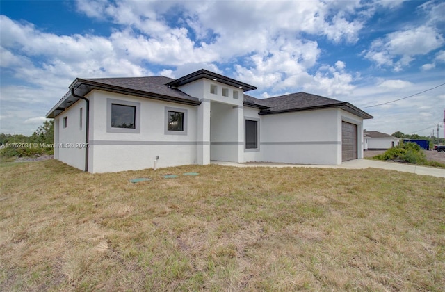 prairie-style home with a garage, a front lawn, concrete driveway, and stucco siding