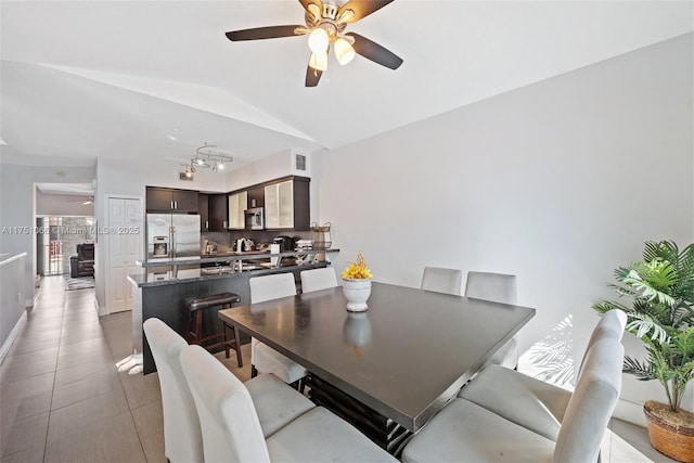 dining space with vaulted ceiling, light tile patterned floors, visible vents, and ceiling fan