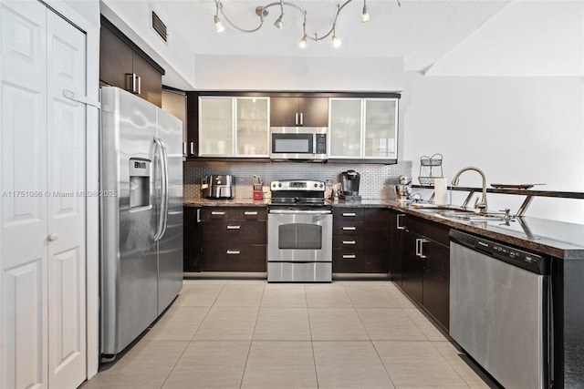 kitchen with visible vents, backsplash, appliances with stainless steel finishes, a peninsula, and a sink