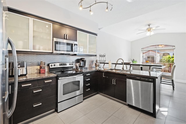 kitchen featuring a sink, stainless steel appliances, backsplash, and dark stone counters