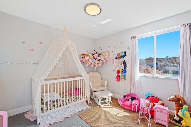 bedroom featuring a nursery area and baseboards