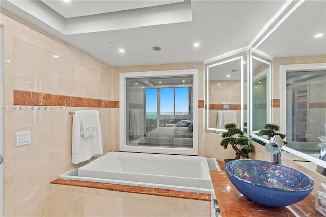 bathroom with a garden tub, tile walls, and vanity