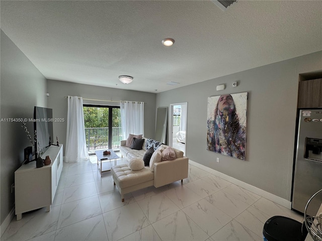 living area featuring marble finish floor, a textured ceiling, and baseboards