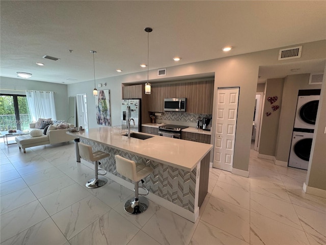 kitchen featuring marble finish floor, light countertops, visible vents, appliances with stainless steel finishes, and stacked washing maching and dryer