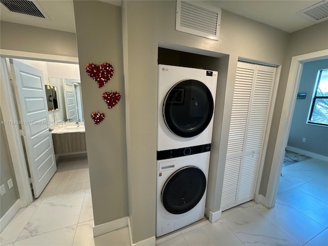 laundry room with laundry area, marble finish floor, stacked washing maching and dryer, and visible vents