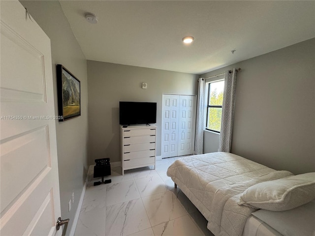 bedroom with marble finish floor, a closet, and baseboards