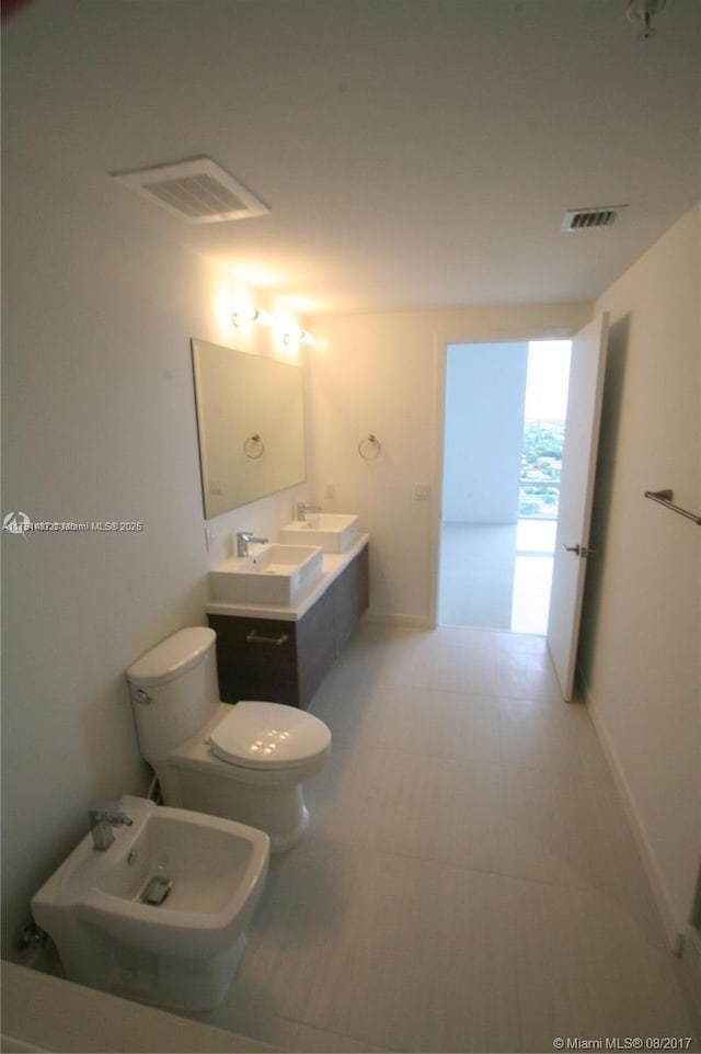 bathroom with double vanity, visible vents, toilet, a bidet, and a sink