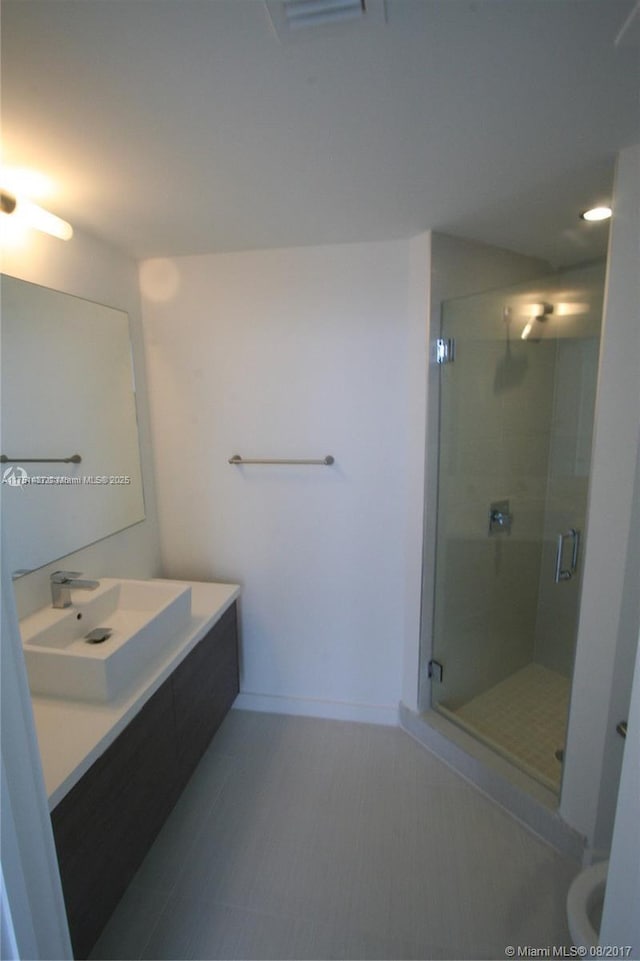 full bathroom featuring a stall shower, baseboards, and vanity