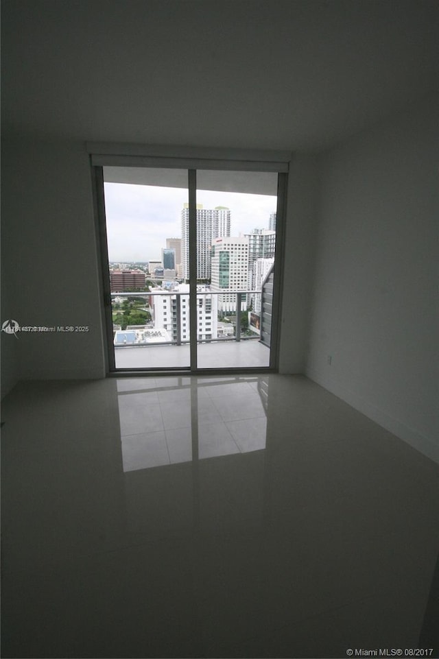 empty room featuring tile patterned flooring, expansive windows, and a city view